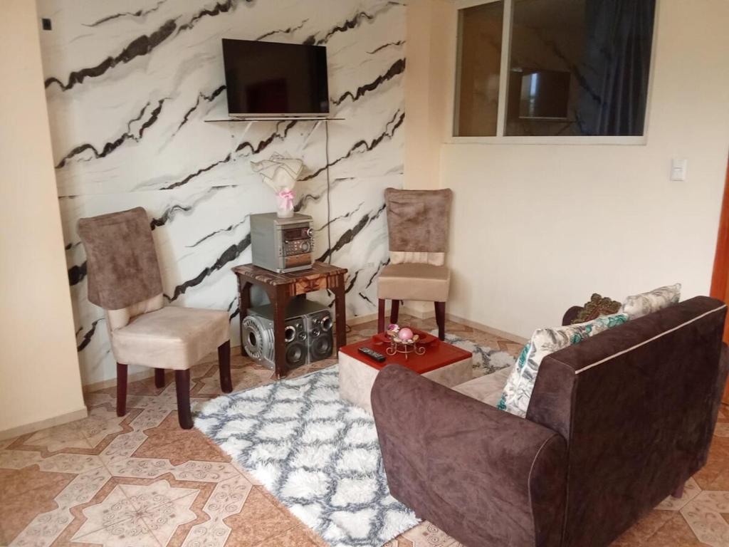 a living room with two chairs a couch and a tv at Entire apartment in Ambato Ficoa in Ambato