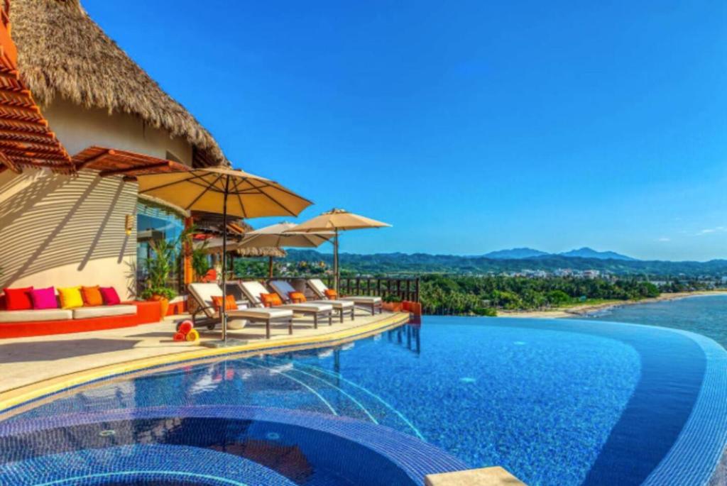 a resort infinity pool with chairs and umbrellas at Luxury Villa Paloma Blanca in Cruz de Huanacaxtle