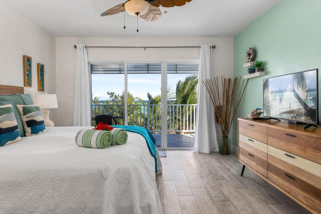 ein Schlafzimmer mit Bett und Fernseher und Balkon in der Unterkunft The Blue Iguana at Cottages in Sand Bluff