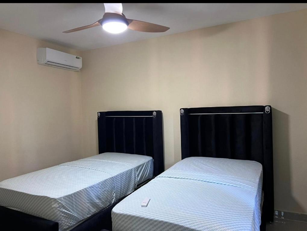two beds in a room with a ceiling fan at Mi refugio 2 in San Fernando de Monte Cristi