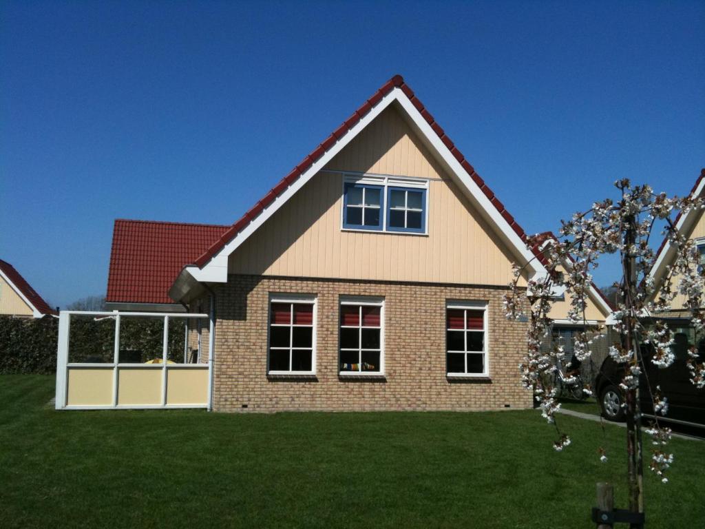 uma casa com um relvado verde em frente em Vakantiehuis Zeeduinenbos em Schoorl