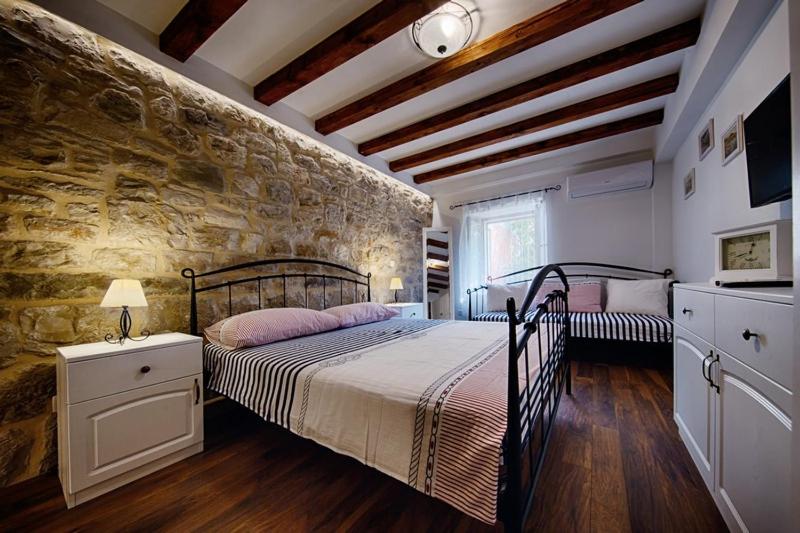 a bedroom with a bed and a stone wall at Riva Suite 1 in Komiža