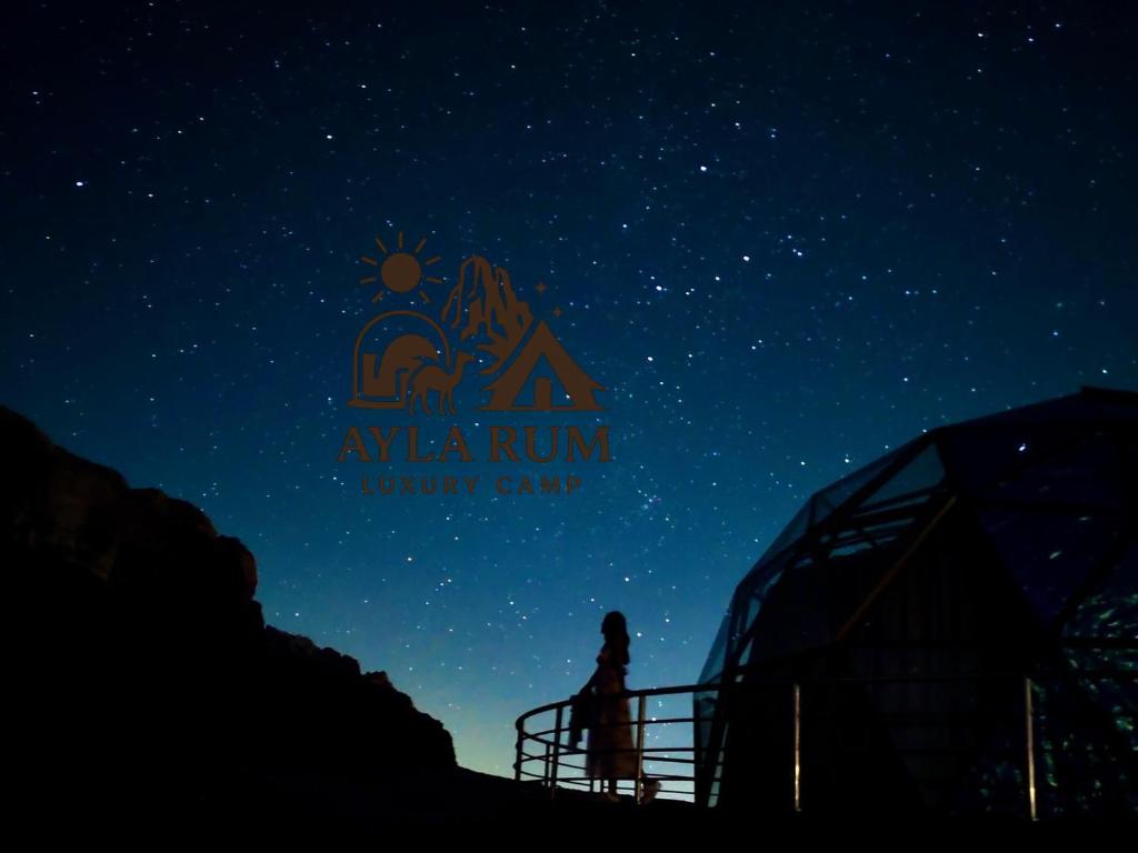 a person standing under a starry sky at night at ALYA RUM LUXURY Camp in Wadi Rum