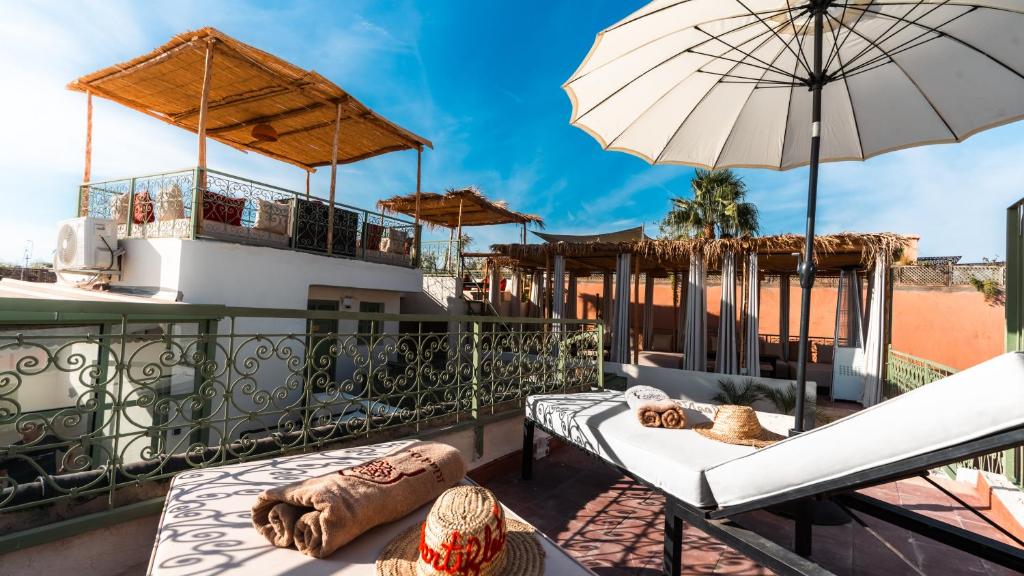 a balcony with two beds and an umbrella at Riad Dar Tiflet in Marrakech
