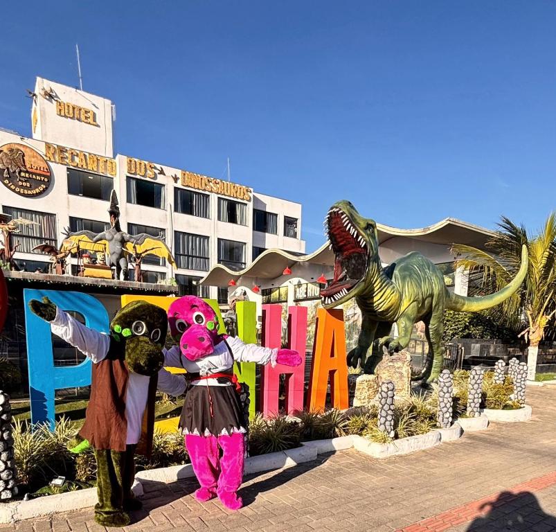two people in dinosaur costumes standing in front of a building at Hotel Recanto dos Dinossauros in Penha
