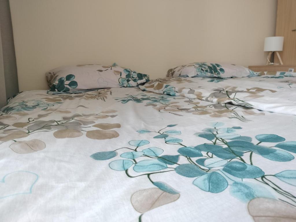 a bed with a blanket with blue flowers on it at Quiet in the City Wrocławska in Kraków