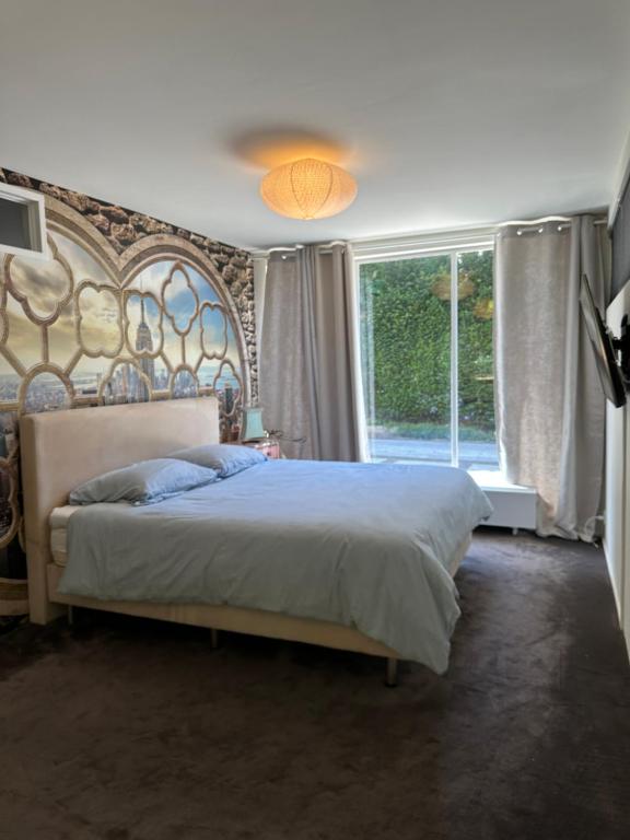 a bedroom with a large bed and a large window at Villa Vista in Wassenaar