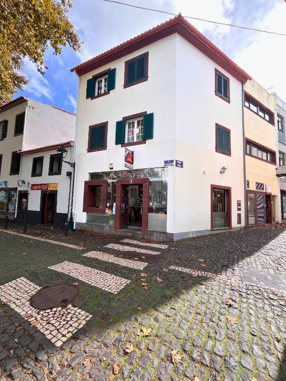 a white building on a cobblestone street at Machico Village Apartment - Private terrace & car park in Machico
