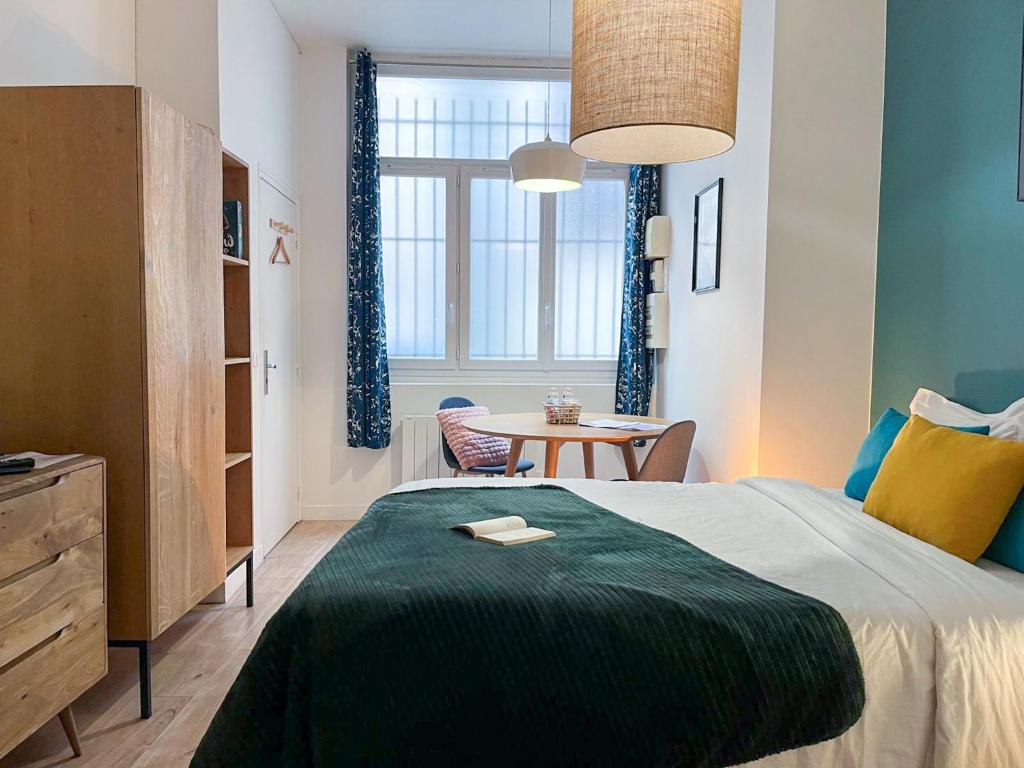 une chambre avec un lit et une table dedans dans l'établissement L'Oasis Rouennais - Hypercentre - Gare rive Gauche, à Rouen