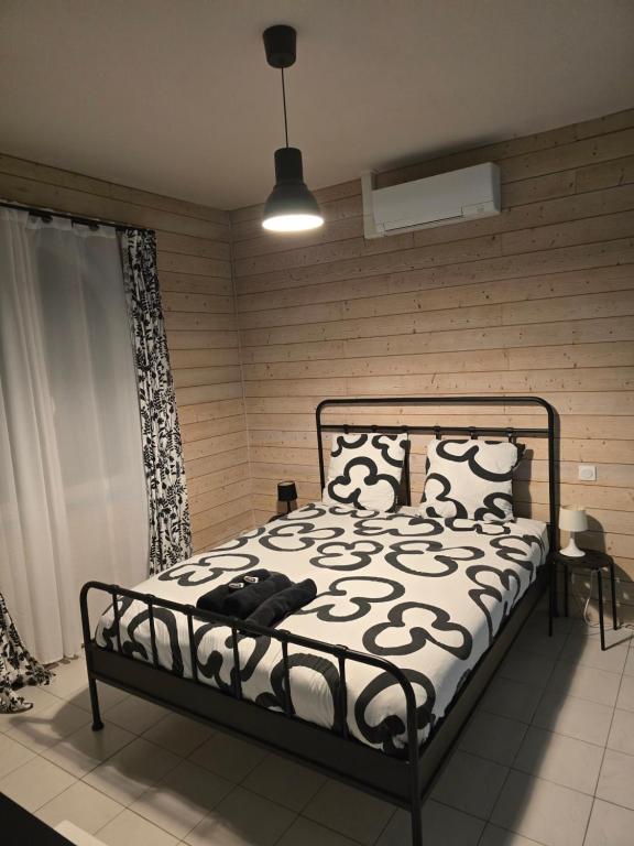 a bedroom with a bed with a black and white comforter at Gîte Horizons Landais Séjour professionnel et vacances dans les Landes in Pontonx-sur-lʼAdour