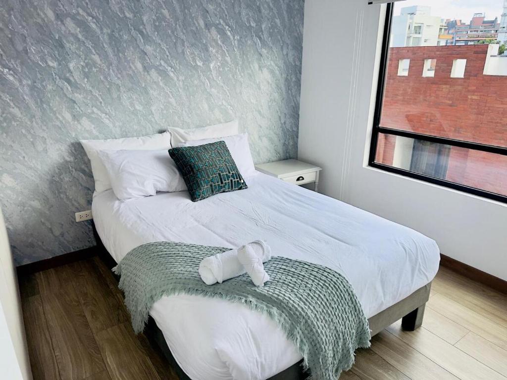 una camera da letto con un grande letto bianco e una finestra di Departamento 2 dormitorios Quiteño Libre a Quito