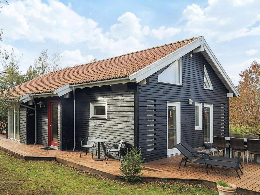 una pequeña casa negra con terraza de madera en 4 star holiday home in Væggerløse, en Bøtø By