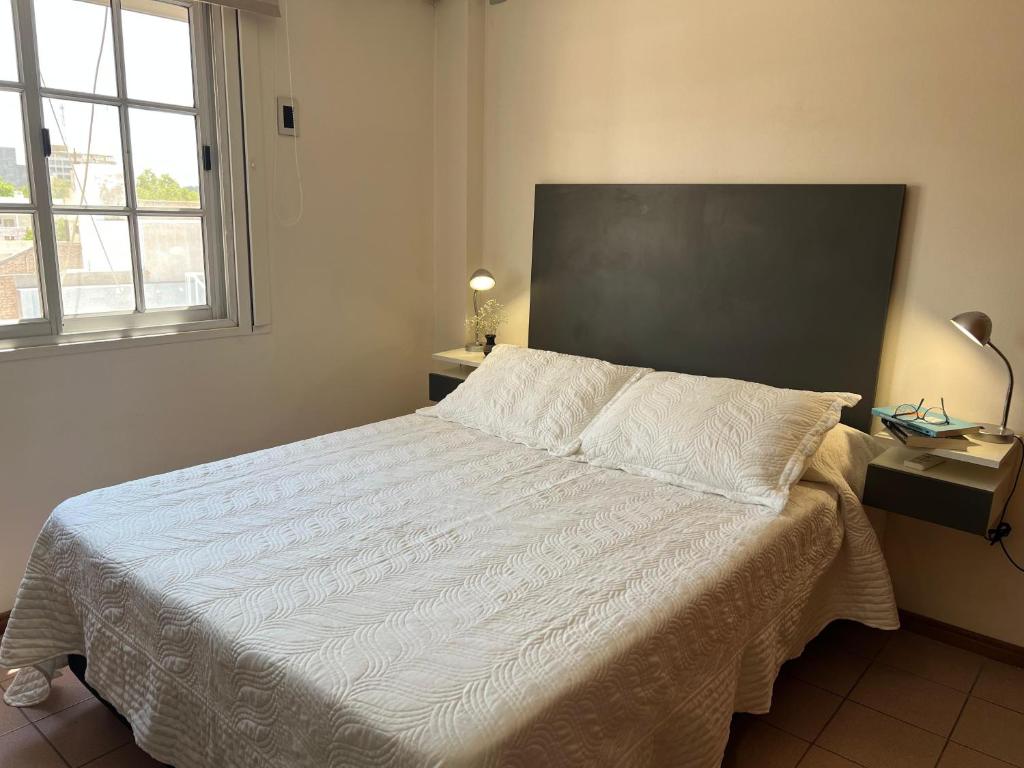 a bedroom with a large white bed with a window at Urbano San Juan in San Juan