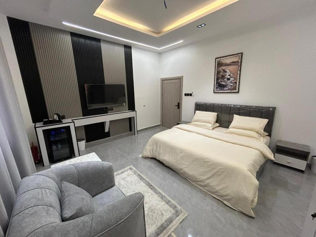 a bedroom with a bed and a couch and a tv at قمرة قباء Quba moon3 in Al Madinah