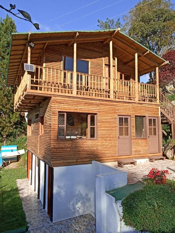 a large wooden house with a deck on top at Cabañas 4 Caminos in San Francisco