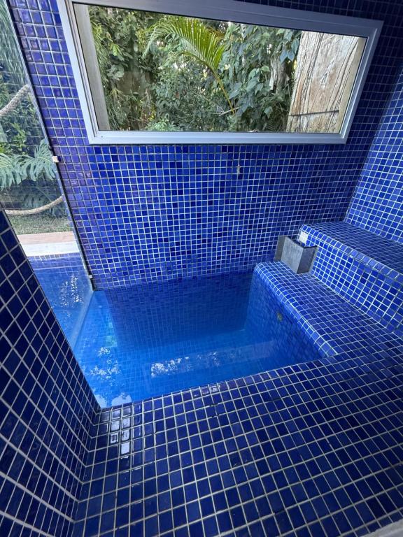 ein blau gefliestes Bad mit einer Badewanne und einem Fenster in der Unterkunft Casa Riviera Prime in Colônia de Férias