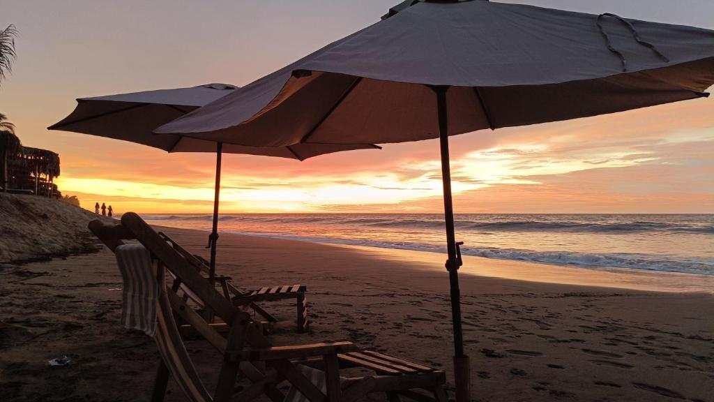 ein paar Stühle und ein Sonnenschirm am Strand in der Unterkunft Villa Naylamp Loft 2 familiar playa pocitas in Máncora