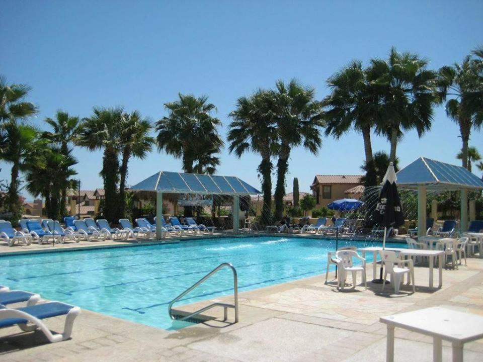 a swimming pool with chairs and tables and palm trees at Casa Talebi El Dorado Ranch San Felipe WiFi in Playa El Paraíso