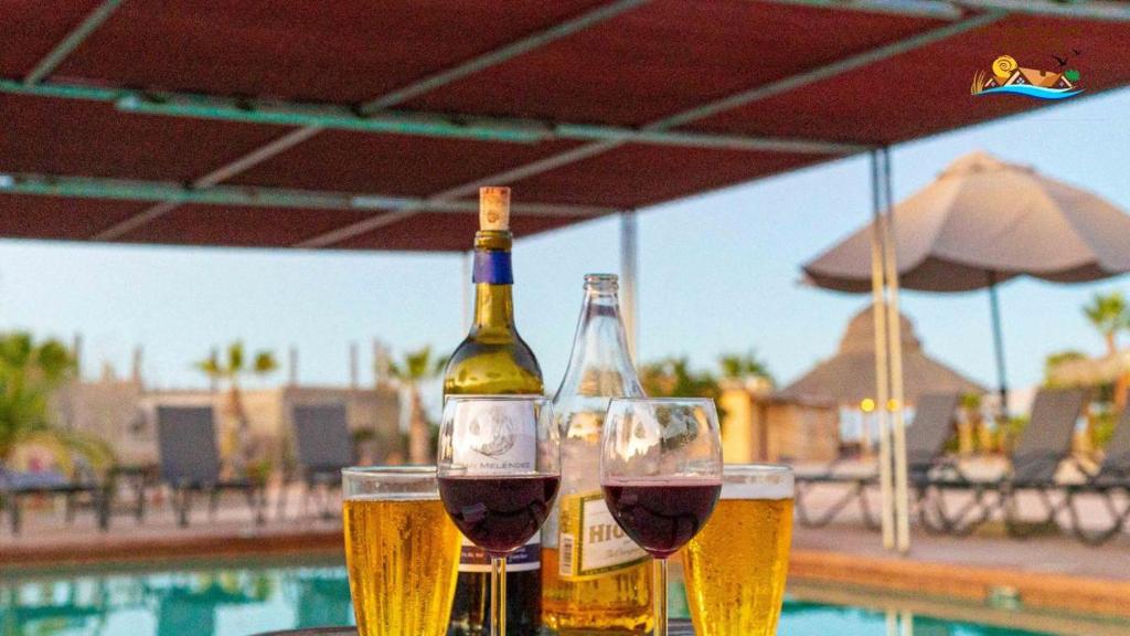 two bottles of wine and glasses on a table near a pool at Beach Bungalow, Pool and direct Beach Access in San Felipe
