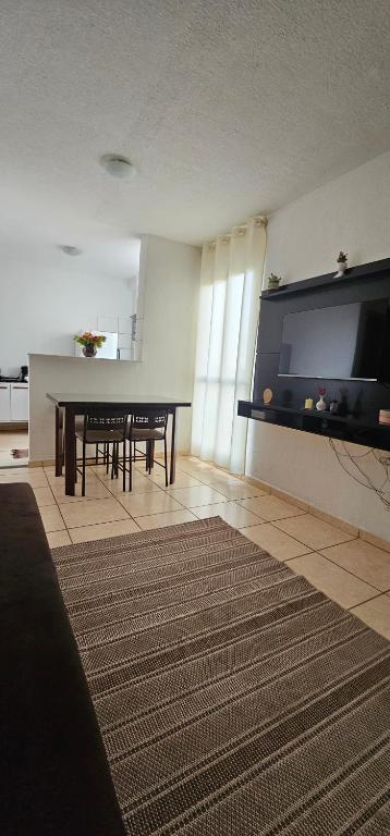 a living room with a table and a large flat screen tv at Doce refúgio - Aconchegante e completo in Uberaba