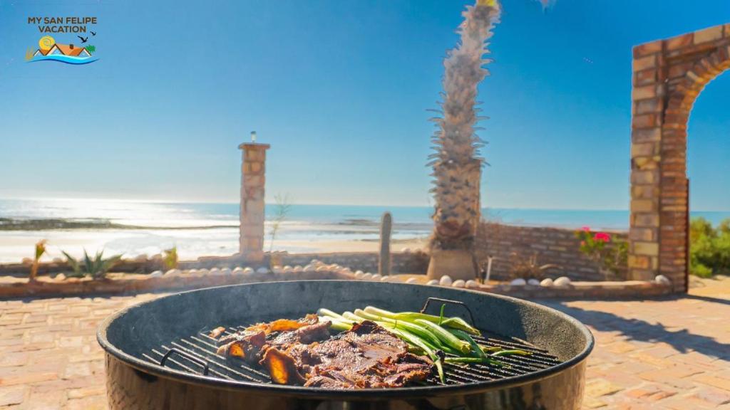 a grill with meat and vegetables in front of the beach at Rancho Percebu Beach Studio 4 in San Felipe