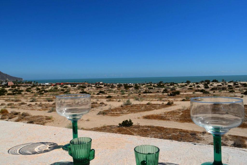 two wine glasses on a table with a view of a desert at Casa Rubio del Mar - Monthly Rentals Welcome in San Felipe
