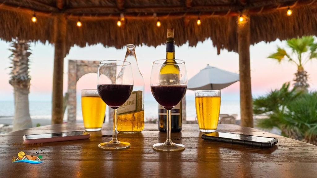 a table with three glasses of wine and a bottle at 3 bedroom Beach side home away from home in San Felipe