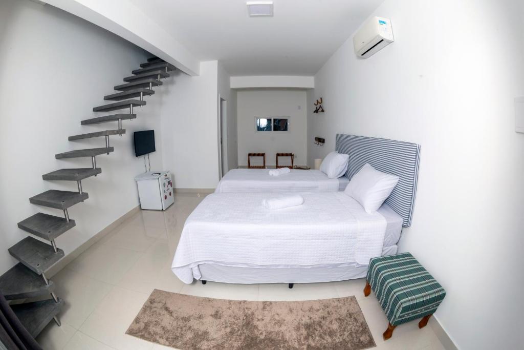 a white bedroom with a bed and a staircase at Hi Adventure in Florianópolis