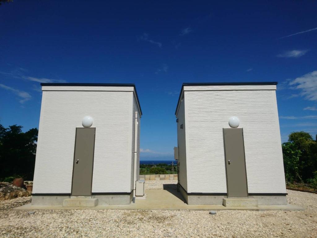 two white storage buildings sitting on top of gravel at 与論島の宿とーとぅがなし in Yoron
