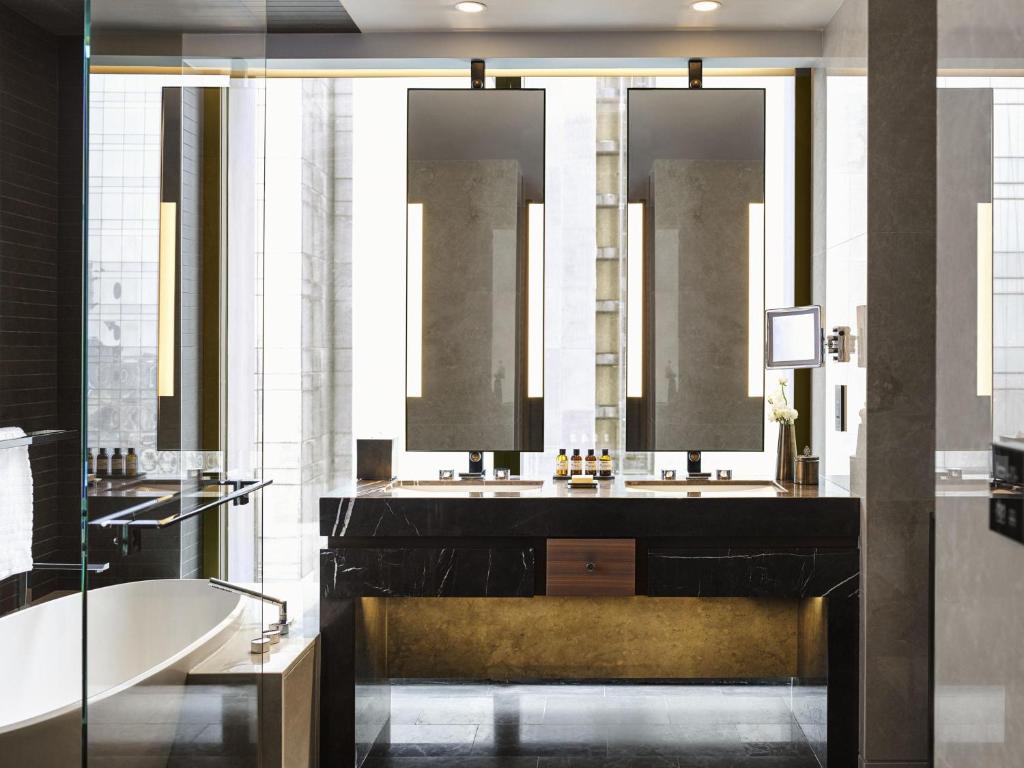 a bathroom with a tub and a sink and mirrors at Fairmont Quasar Istanbul Hotel in Istanbul