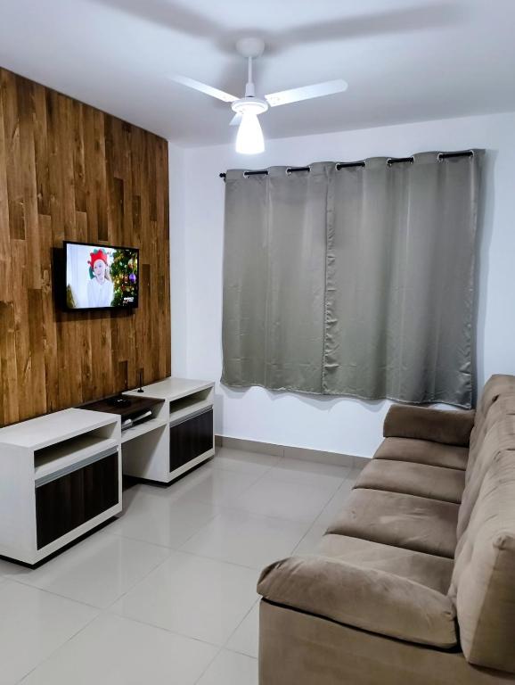 a living room with a couch and a flat screen tv at Apartamento aconchegante in Maringá