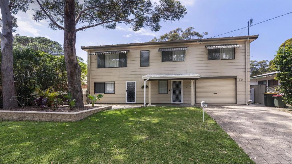 een huis met een garage en een grasveld bij 30 Curlew Avenue Hawks Nest in Hawks Nest