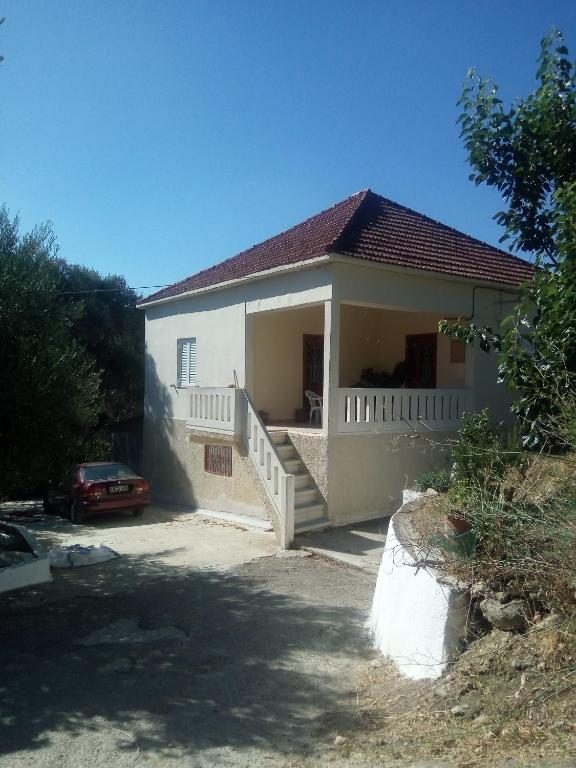 una pequeña casa blanca con porche y coche en Olympia House, en Káto Karés