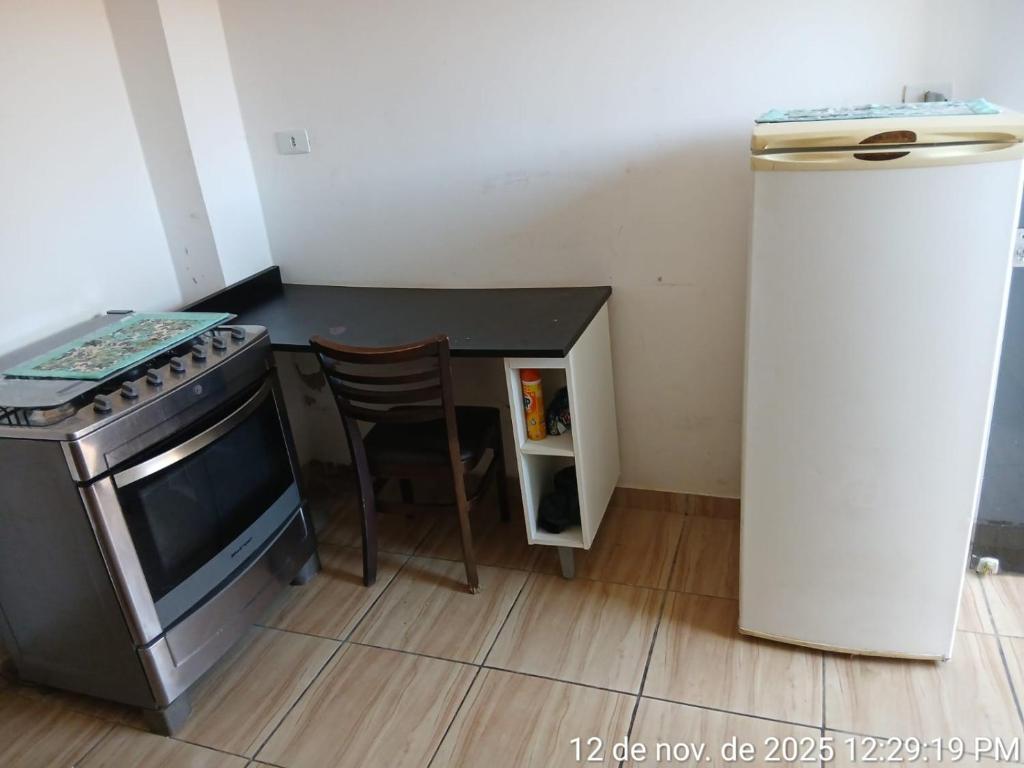 eine Küche mit einem Herd, einem Tisch und einem Kühlschrank in der Unterkunft Kitnet Micro Sobrado in Telêmaco Borba