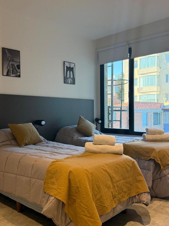 a bedroom with two beds and a large window at Departamento excelente ubicación in Comodoro Rivadavia