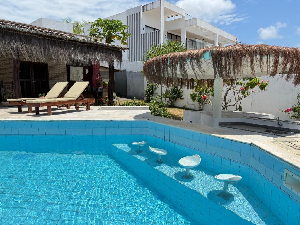a swimming pool with stools in front of a building at Oceana Suites Vila da Mata in Pipa