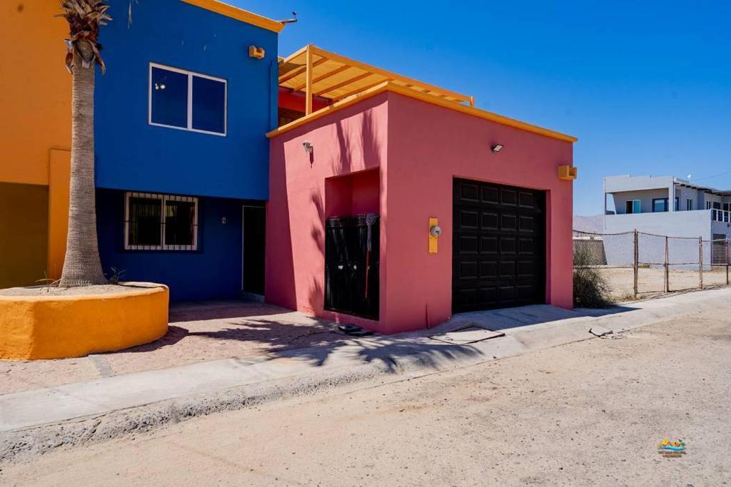 a pink and blue building with a garage at Condo 4, In town and steps to the beach and Malecon in San Felipe