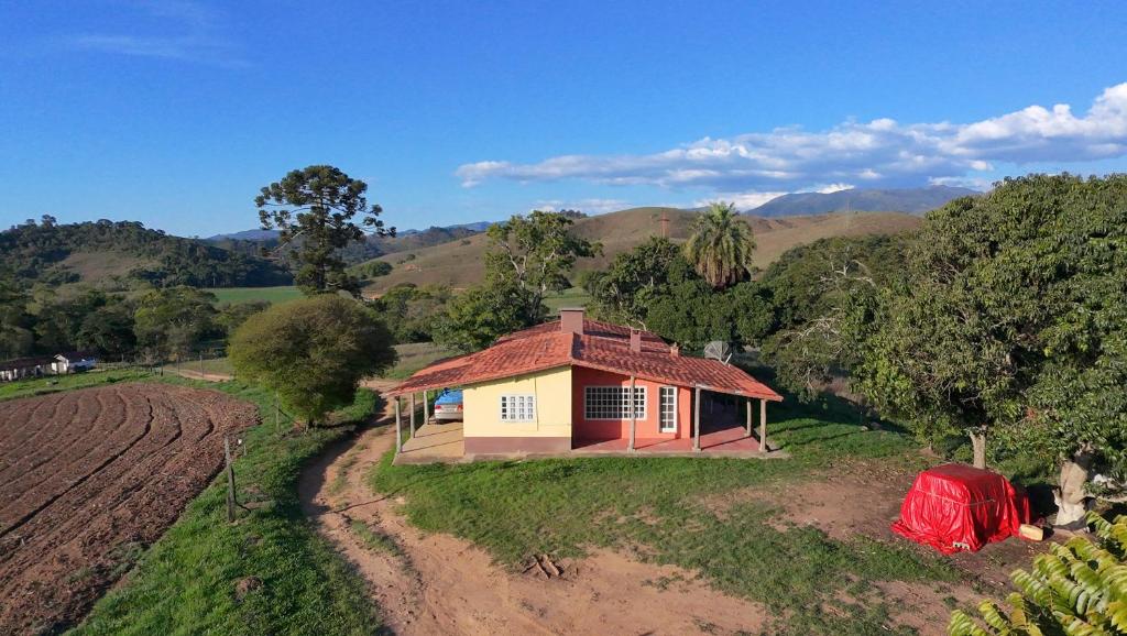 a small house in the middle of a field at Sítio com casa Rústica Itamonte in Santana do Capivari