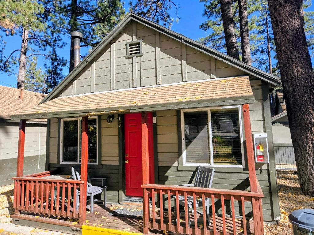 ein kleines Haus mit einer roten Tür und einer Veranda in der Unterkunft Big Bear Frontier in Big Bear Lake