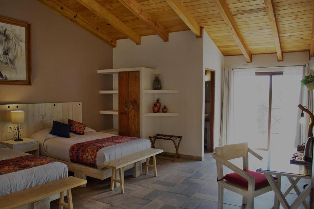 a bedroom with two beds and a table and chairs at Hotel Puerta de Piedra in Tapalpa