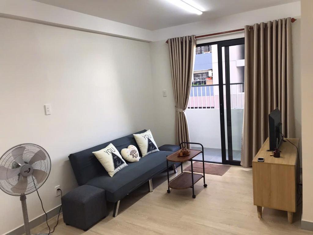 a living room with a blue couch and a fan at Simple House-Simple Life in Long Xuyên