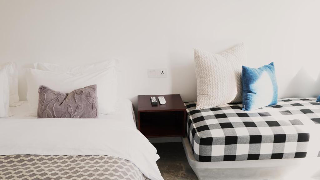 a bedroom with two beds and a night stand with a bedskirts at Serenity Angkor in Phum Pobos