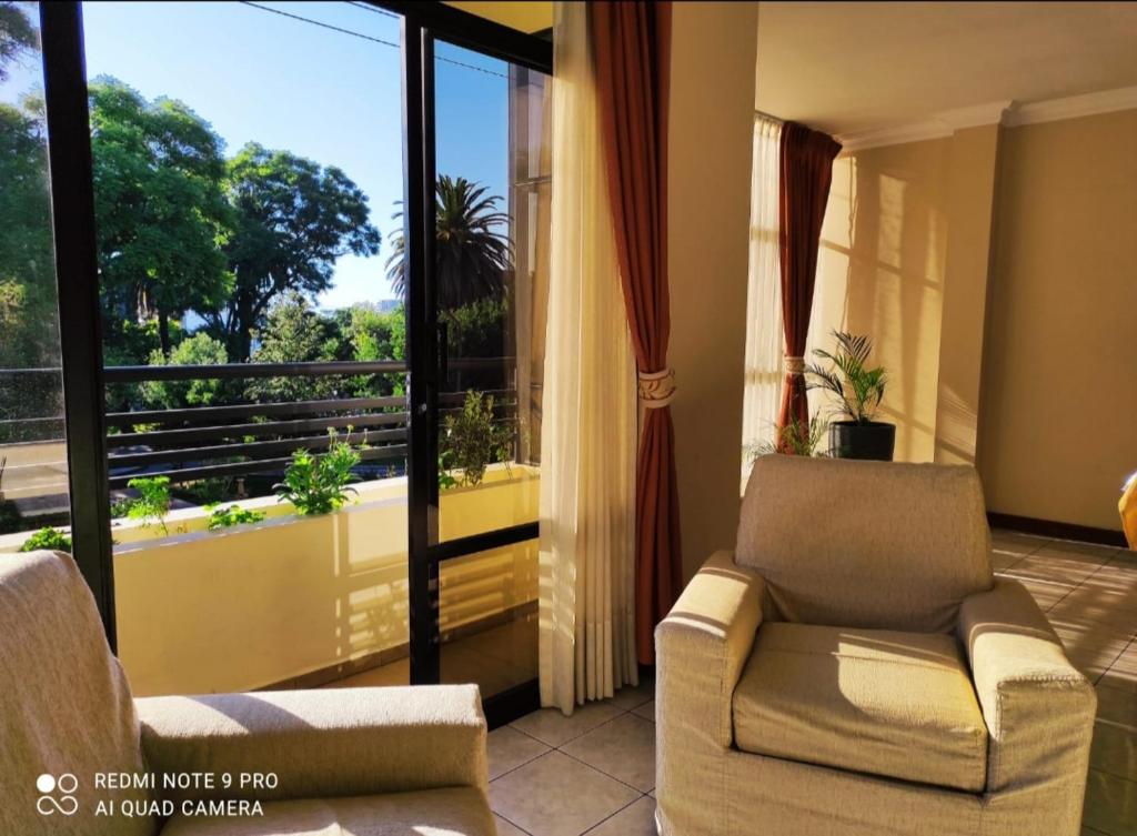 a living room with two chairs and a balcony at Departamentos de Altura in Tarija