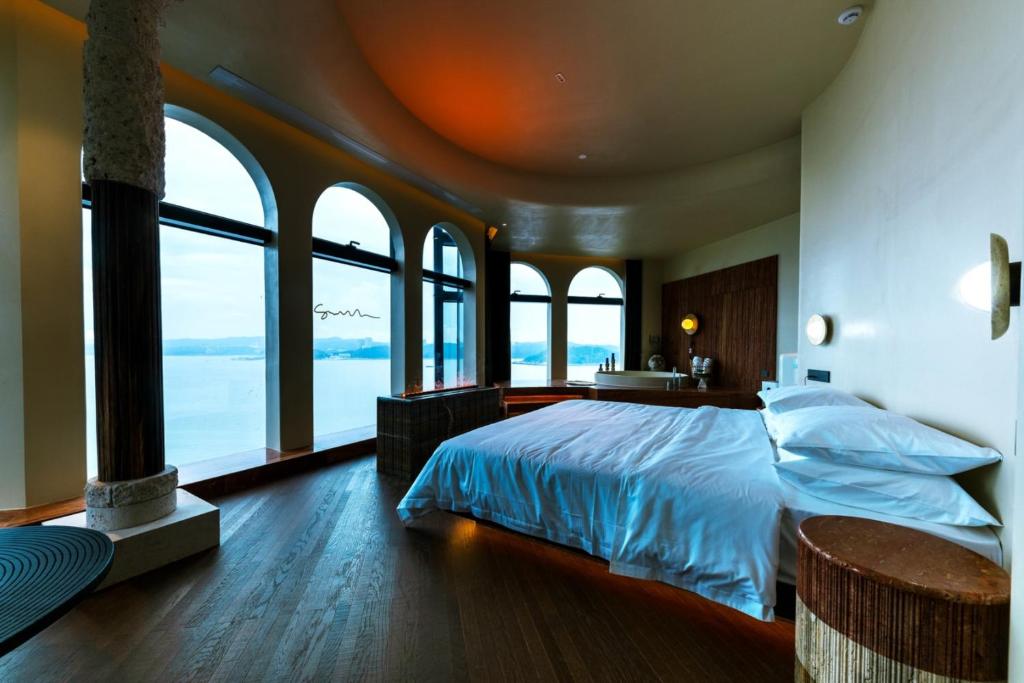 a bedroom with a large bed with large windows at Shanheli Mediterranean Seaside Resort Homestay East Coast Branch in Ma Yu