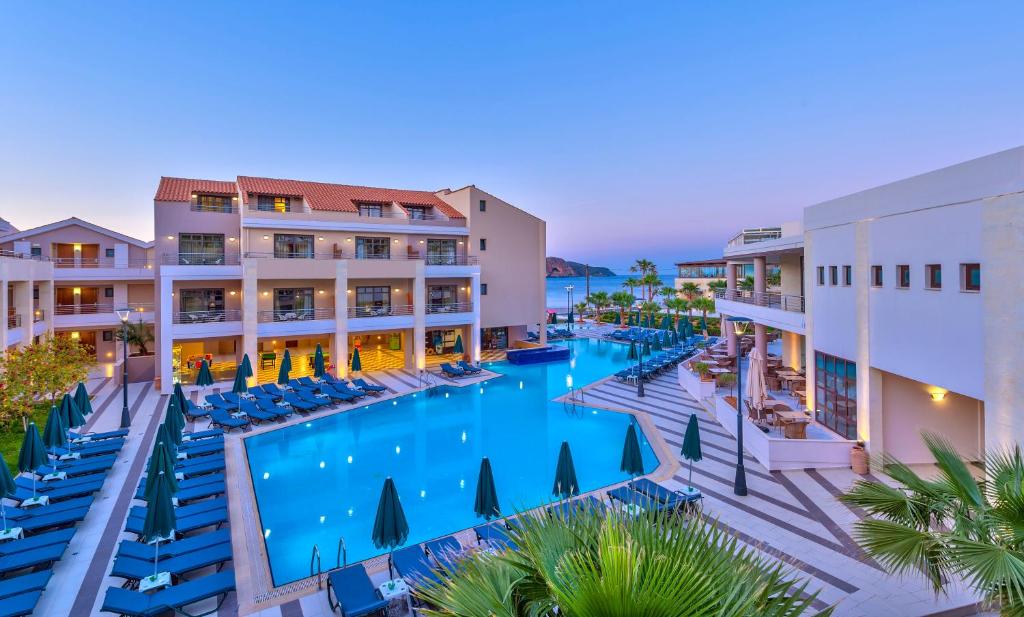 an aerial view of a resort pool with chairs and palm trees at Porto Platanias Beach Resort & Spa in Plataniás