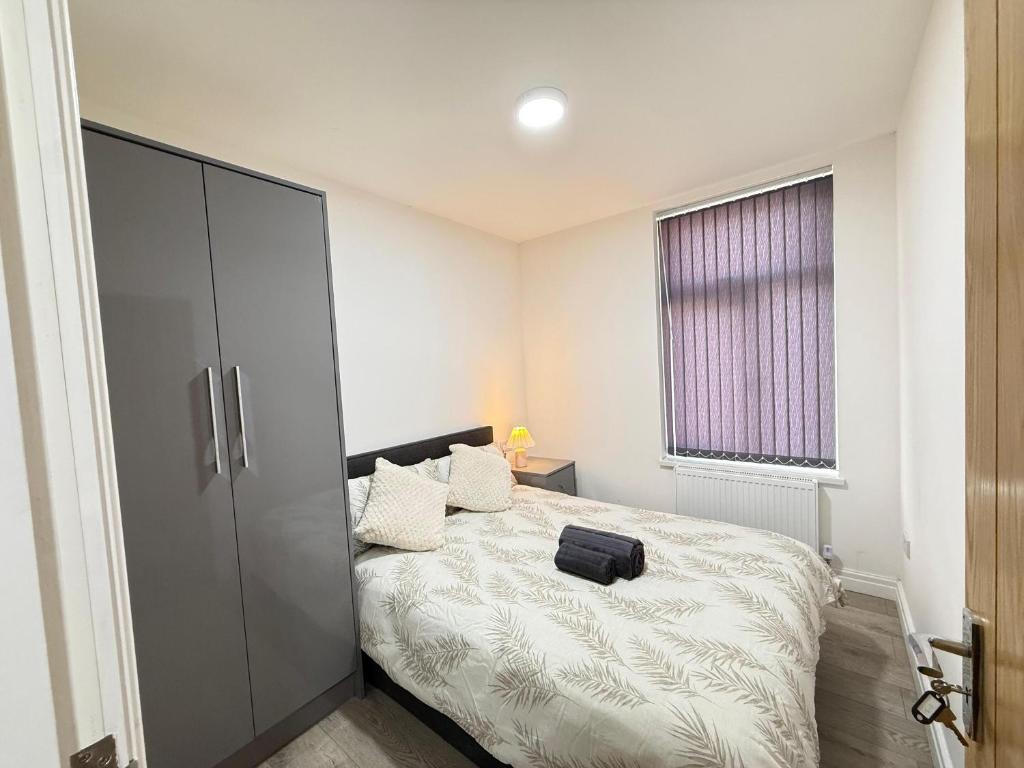 マンチェスターにあるBritlodge Livingのベッドルーム1室(黒いスーツケース付きのベッド1台付)