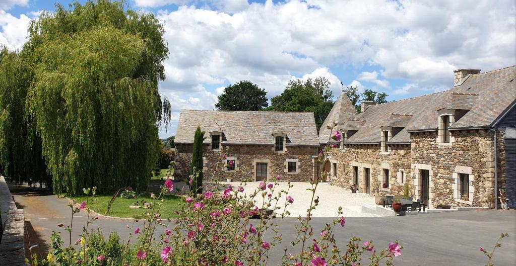 a stone building with pink flowers in front of it at La métairie in Plédèliac