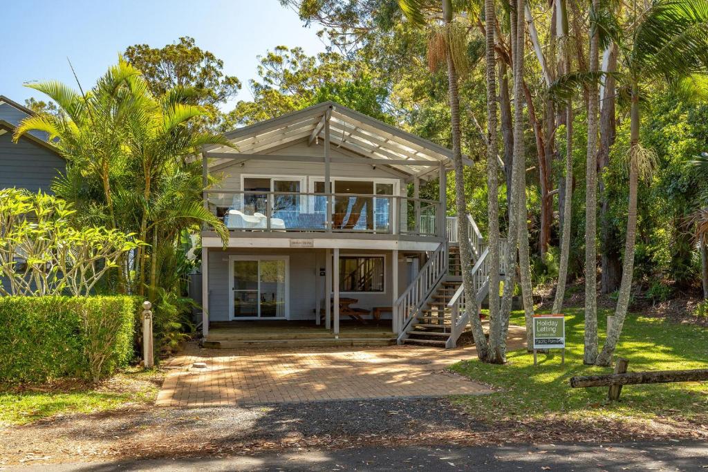 a home with palm trees in front of it at Reflections in Smiths Lake