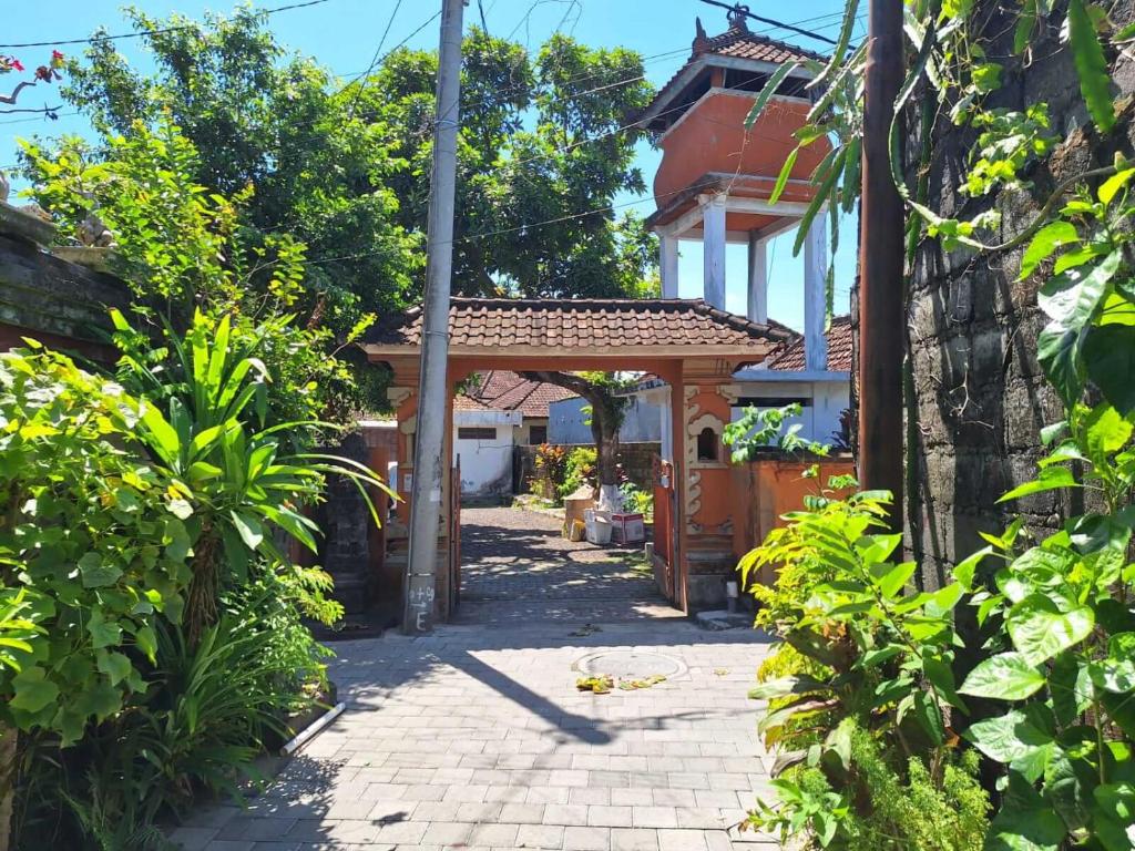 ein Weg, der zu einem Haus mit einem hölzernen Torbogen führt in der Unterkunft Warmadewa 7, Sanur Guesthouse near beach in Sanur