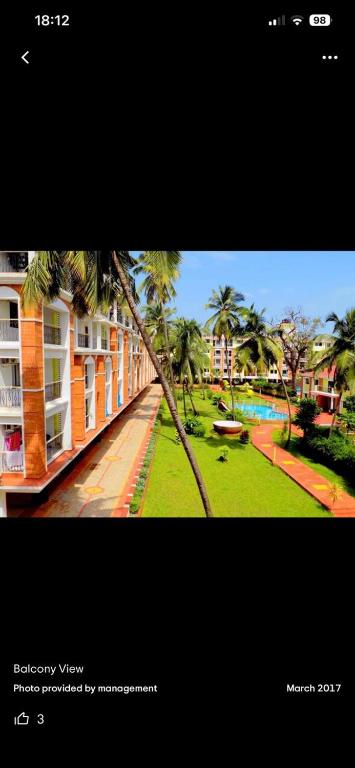 a picture of a building and a park with palm trees at Sun & Sand Candolim Goa in Candolim